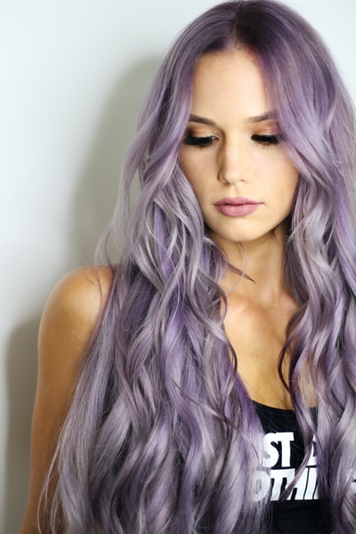 紫色头发，黑色上衣，倚在墙上的女人